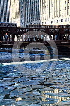 Two elevated `el` trains cross Chicago River during morning rush hour on a frigid, winter morning in Chicago.