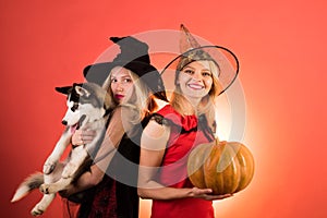 Two sexy Halloween girls with pumpkin. Festive halloween design. Emotional young women in halloween costumes on party