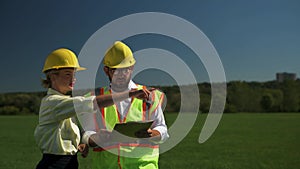 Two employees of an alternative power plant talking about a scheme of solar panels. Engineers talk about the project for the