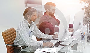 Two employees , sitting in front of computer