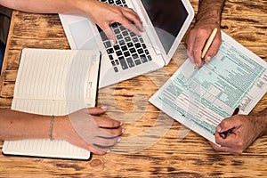 two employees at work fill out tax forms 1040 at the office desk.