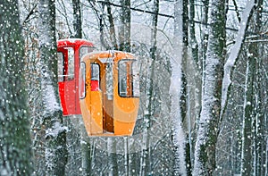 Two empty cableway cabines on a winter forest backdrop. Travel background.