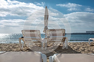 Two empty chaise-lounges on the beach in the city of Costa Teguise