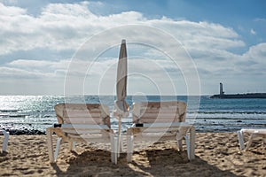 Two empty chaise-lounges on the beach in the city of Costa Teguise