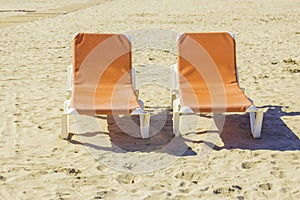 Two empty chaise lounges on the sand