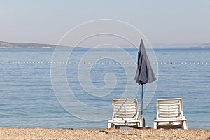 Two empty deck chair and a blue parasol