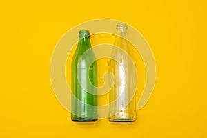 Two empty glass bottle on a yellow background. Eco-friendly packaging, waste recycling concept, glass waste, rubish sort photo