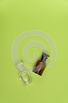 Two empty glass bottles on green background. Perfume, medicine, chemistry background.