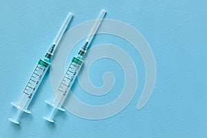 Two empty medical syringes close-up on blue background with space for text