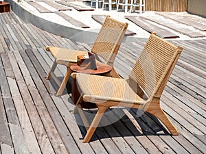 Two empty modern cozy brown rattan chairs decoration on outdoor wooden deck on summer sunny day.