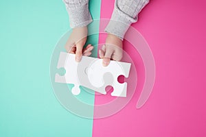 two empty paper white pieces of puzzles in female hands, puzzle connected