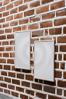 Two empty picture frames hanging on a brick wall. Generative AI image. Mockup.