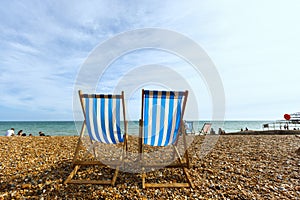 Two empty striped folding beach chairs on seacoast in Brighton, unknown people