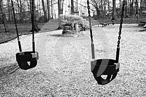 Two empty swings at the playground in the park.