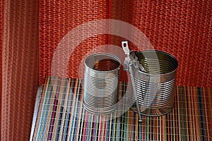 Two empty tin cans with an opener.