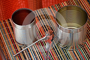 Two empty tin cans with an opener.