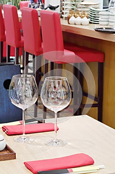 Two empty transparent wine glasses stand at table