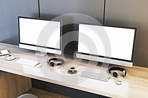 Two empty white gaming computer displays on desk with coffee cups and headsets. Place for your advertisement. Gaming club concept