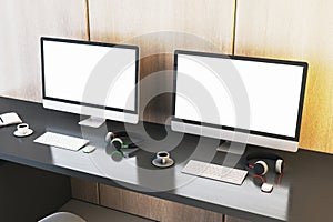 Two empty white gaming computer monitor on desk with coffee cups and headsets. Place for your advertisement. Gaming club concept.