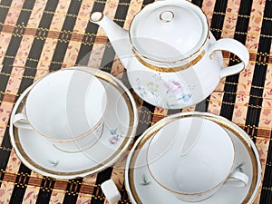 Two empty white porcelain cup and teapot on the table