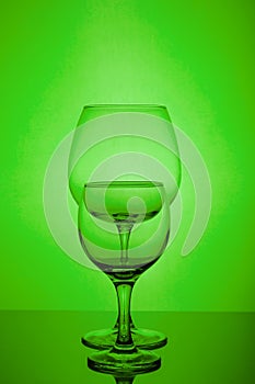 Two empty wine glass on green background