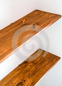 two empty wooden shelves on a white wall