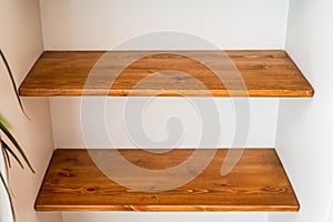 two empty wooden shelves on a white wall