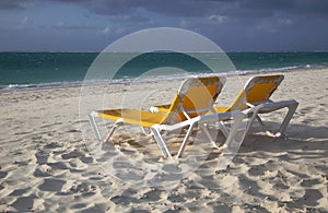 Two empty yellow lounge chairs on the beach