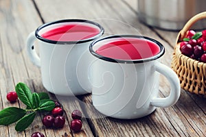 Two enameled mugs of cranberry juice or morsel. A cranberry drinks, basket of berries and pan.