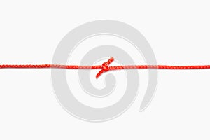 The two ends of a red rope are tied into a knot on a white isolated background