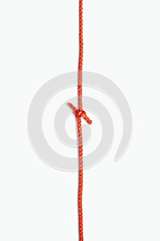 The two ends of a red rope are tied in a knot on a white vertical background