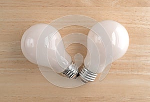 Two energy saving light bulbs on a wood table