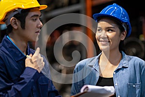 Two engineer or manager wearing safety helmet standing in the automotive part warehouse. Woman looking at man and smile. Team work