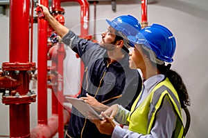 Two engineer or technician worker discuss about red pipe system in the construction site to maintenence and fix the problem