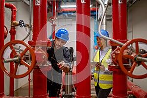Two engineer or technician worker discuss about red pipe system in the construction site to maintenence and fix the problem
