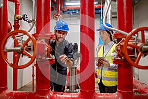 Two engineer or technician worker discuss about red pipe system in the construction site to maintenence and fix the problem