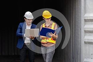 Two engineer worker hold a laptop, document for checking a quality of containers box from cargo ship