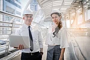 Two engineer worker with safety helmet meeting with laptop working outside factory