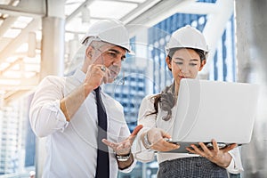 Two engineer worker with safety helmet meeting with laptop working outside factory