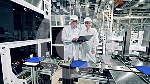 Two engineering experts are observing conveyor with solar cells
