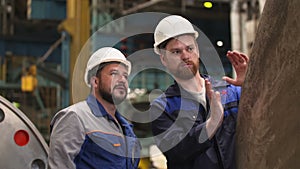 Two engineers discuss important stages of construction in heavy industry factory