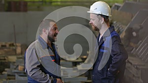 Two engineers discuss stages of construction in heavy industry factory. welder background