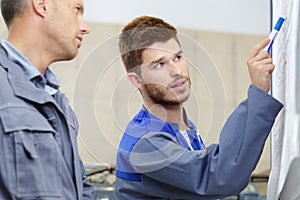 two engineers and finger point to whiteboard