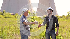 Two engineers in hard hats shaking hands.