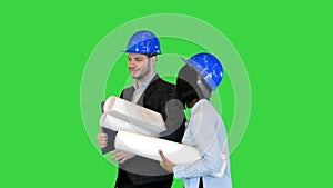 Two engineers in hardhat walk discuss blueprint Young diverse team of architects designers speaking on a Green Screen