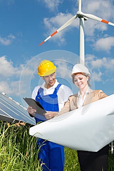 Two engineers look at construction plan of solar panels