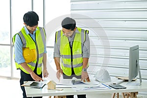 Two engineers man looking at blueprint drawing project plan on the table