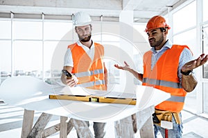 Two engineers man looking at project plan on the table in construction site