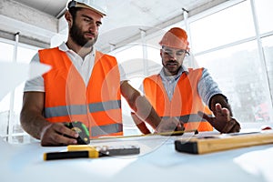 Two engineers man looking at project plan on the table in construction site
