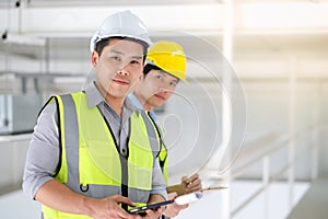 Two engineers man standing in the site. Engineer holding  tablet and smile under sunlight with copy space